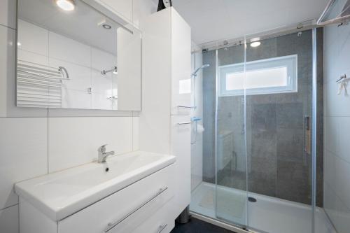 a white bathroom with a sink and a shower at Park Haerendycke Lod4207 in Wenduine