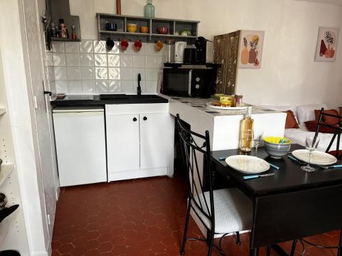 une cuisine avec une table et des placards blancs dans l'établissement Au coeur du village provençal, à Tourtour