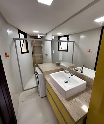 a bathroom with a white sink and a tub at Jubiabá - 214C - Vista Mar in Ilhéus