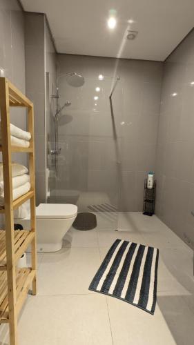 a bathroom with a shower and a toilet and a rug at Casa em Aldeia Pescadores in Vila Nova de Gaia