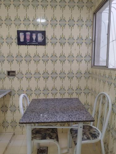 a table and two chairs in a room with wallpaper at Apto tipo Casa 10 com 2 quartos bem grande Praia da Costa Centro Ar Condicionado Internet Mobiliado Geladeira Fogao TV in Vila Velha