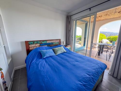 une chambre avec un lit bleu et un balcon dans l'établissement Appartement rénové à Grimaud dans le Golfe de Saint-Tropez - Les Restanques, à Grimaud