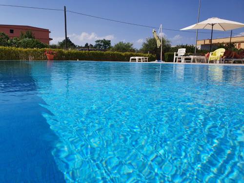ein großer blauer Pool mit Stühlen und einem Sonnenschirm in der Unterkunft Lina apartments A1 in Ginosa Marina