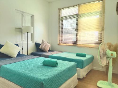 a room with three beds and a fan at The Grove Guesthouse in Patong Beach
