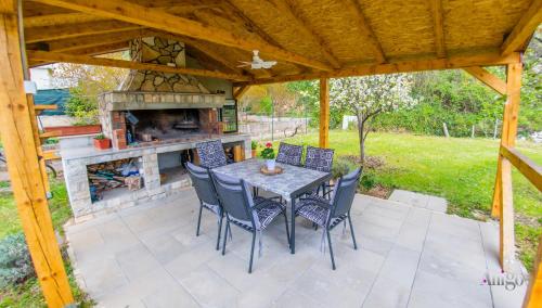 un patio con tavolo, sedie e camino di Bega Apartman a Mostar
