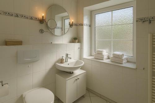 een badkamer met een wastafel, een toilet en een spiegel bij Ferienwohnung Meeresrauschen in Schausende