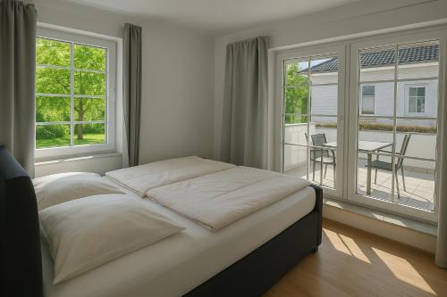 een slaapkamer met een bed en een balkon met een tafel bij Ferienwohnung Meeresrauschen in Schausende