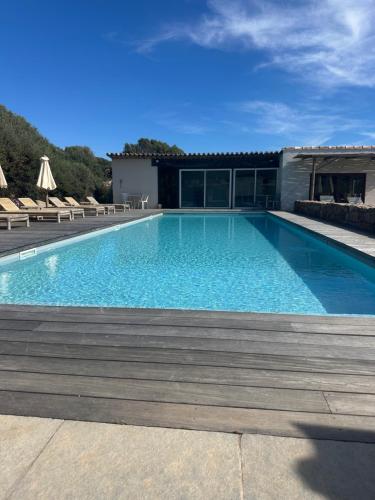 une grande piscine avec des chaises et un bâtiment dans l'établissement les chalets de la Residence A Santa Trinita, à Bonifacio
