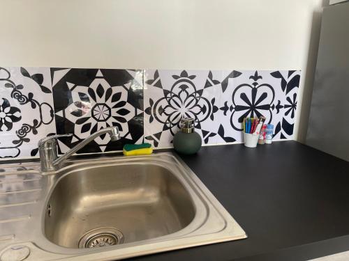 - un comptoir de cuisine avec évier et fleurs sur le mur dans l'établissement L'aventurine NO, à Barbâtre