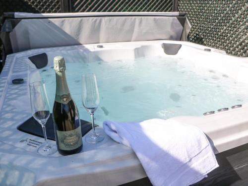 a hot tub with a bottle of wine and two glasses at Rose Cottage in Nottingham
