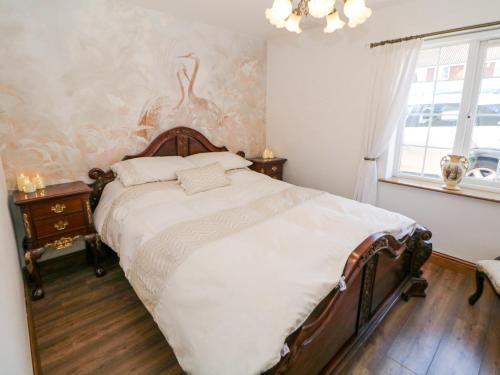 ein Schlafzimmer mit einem großen Bett mit einem hölzernen Kopfteil in der Unterkunft Rose Cottage in Nottingham