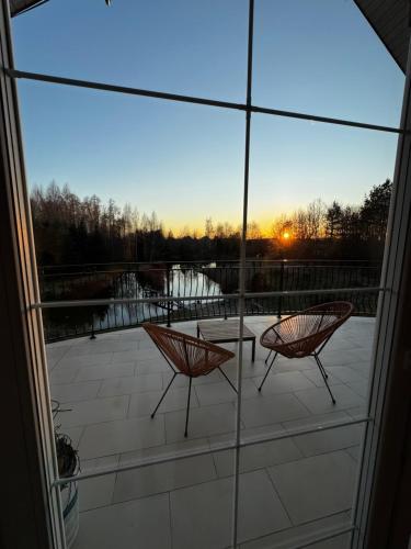 two chairs on a patio with a view of a lake at Apartament Jezioro Łabędzie in Białla