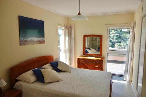 a bedroom with a bed and a mirror and a window at Aylevarroo Penthouse in Caniço