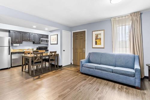 a living room with a blue couch and a kitchen at SureStay Studio by Best Western Pensacola in Pensacola