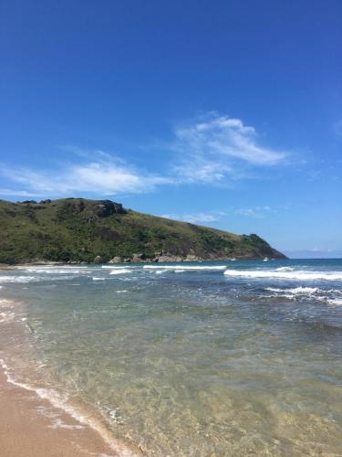 a beach with the ocean and a hill in the background at Mangará Hostel e Hospedaria in Ilhabela