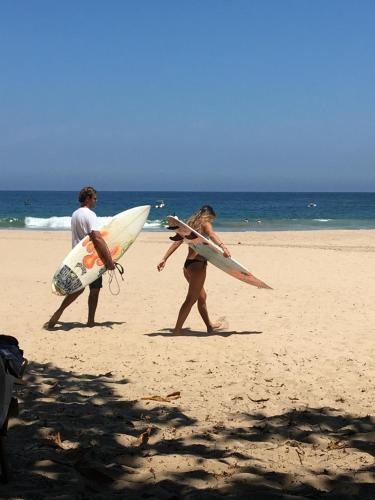 a couple of people walking on the beach with surfboards at Mangará Hostel e Hospedaria in Ilhabela