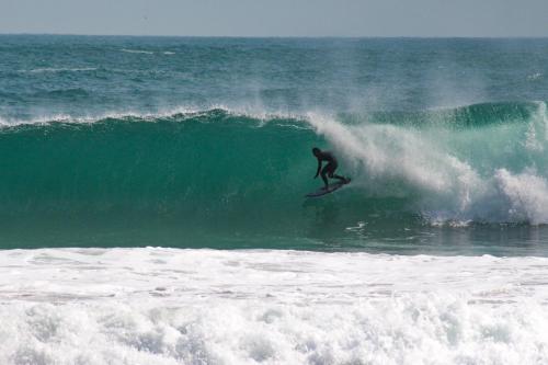 a man riding a wave on a surfboard in the ocean at Mangará Hostel e Hospedaria in Ilhabela