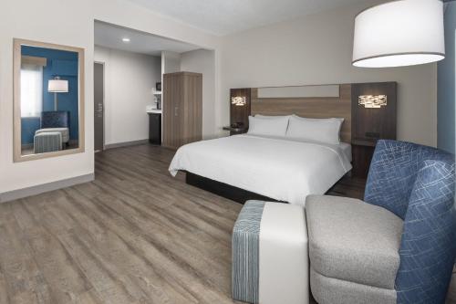 a hotel room with a bed and a chair at Holiday Inn Express & Suites Leesburg - Historic District by IHG in Leesburg