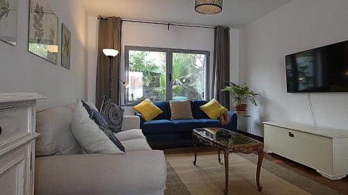 a living room with a blue couch and a window at Madeira Serenity Cottage in Funchal