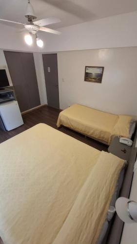 a hotel room with two beds and a ceiling fan at Hotel Mayoral in Rosario