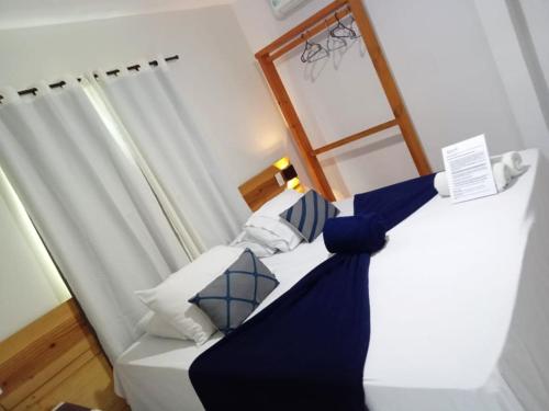 une chambre avec un lit avec des oreillers bleus et blancs dans l'établissement Pousada Aratu, à Fernando de Noronha
