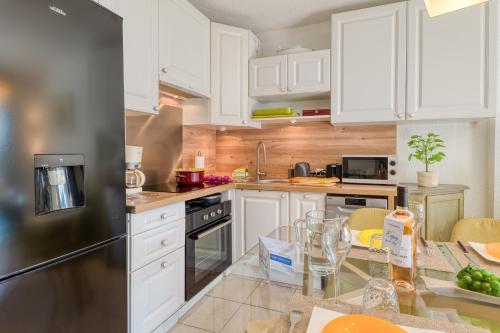 une cuisine avec des armoires blanches et un réfrigérateur en acier inoxydable dans l'établissement Apartment Poseidon - Sea View - Happy Rentals, à Drammont