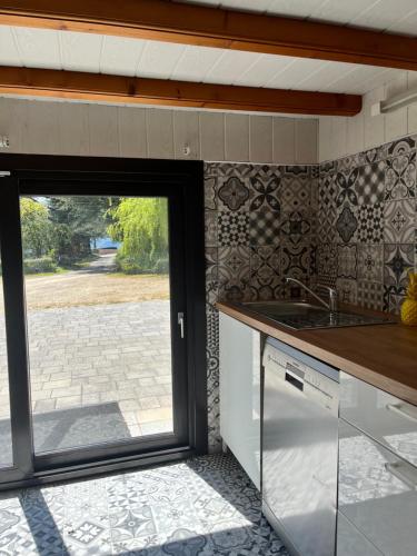 une cuisine avec un évier et une porte coulissante en verre dans l'établissement Gîte Ardéchois avec vue magnifique, à Saint-Jean-de-Muzols