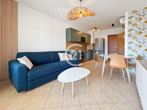 un salon avec un canapé bleu et une table dans l'établissement Victoria Calvi - Appartement T2, à Calvi