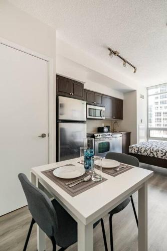 a kitchen with a white table and chairs and a kitchen with a bed at CN Tower Luxe Suites - Prime Downtown Location in Toronto