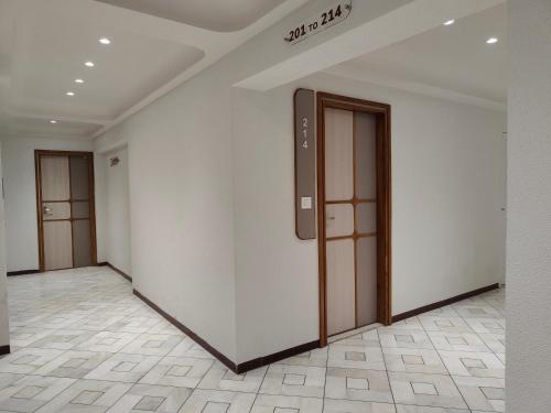 a corridor with white walls and wooden doors at Hotel Kozar in Ahmedabad