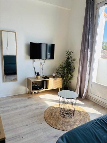 un salon avec une télévision à écran plat et une table dans l'établissement Duplex cosy neuf - wifi - balcon - en bordure de forêt de pins - proche plage, à Saint-Jean-de-Monts