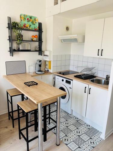 une cuisine avec une table et une machine à laver dans l'établissement Duplex cosy neuf - wifi - balcon - en bordure de forêt de pins - proche plage, à Saint-Jean-de-Monts