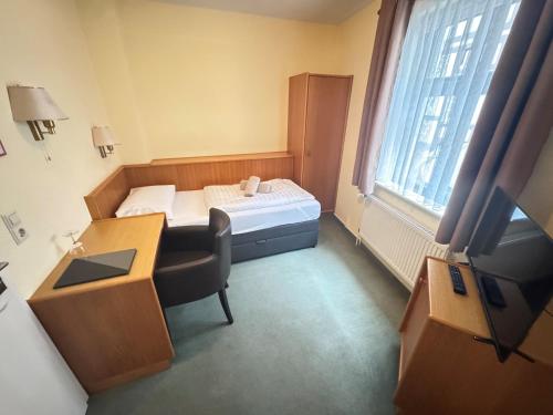 a small room with a bed and a desk and a television at Hotel Müritzlicht in Waren