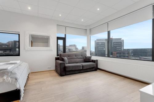 a bedroom with a bed and a chair and windows at Blue Mountain Apartments by Heimaleiga in Reykjavík