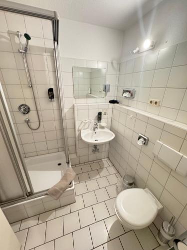 a bathroom with a shower and a toilet and a sink at Hotel Müritzlicht in Waren