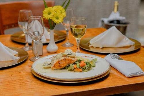 a table with a plate of food and glasses of wine at Holiday Inn Convention Center by IHG in Managua