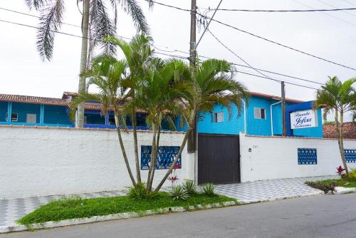 a blue building with palm trees in front of it at Chalé Jofisa in Praia Grande