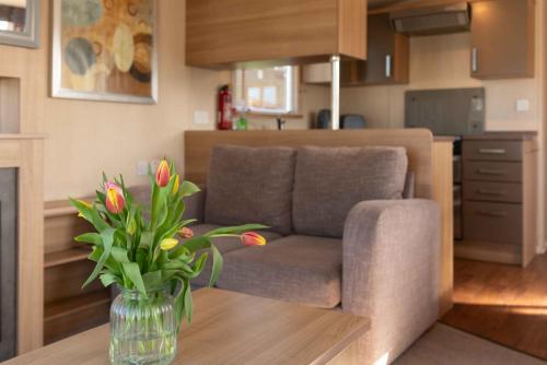 a living room with a couch and a vase of flowers on a table at 24 Woolacombe Heights - 3 Bed - Sleeps 6 - TJS24WH in Ilfracombe
