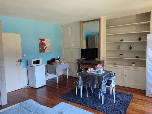 a living room with a table and a television at Chambres d'hôtes chez Sylvie in Donnemain-Saint-Mamès
