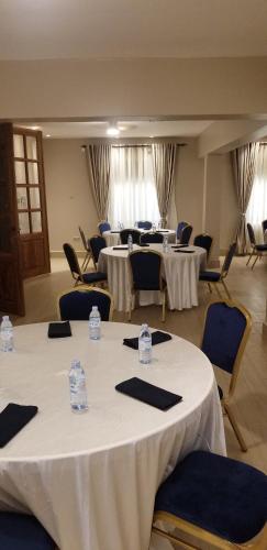 a room with several tables and chairs with white tables at Blue Berries Hotel in Entebbe