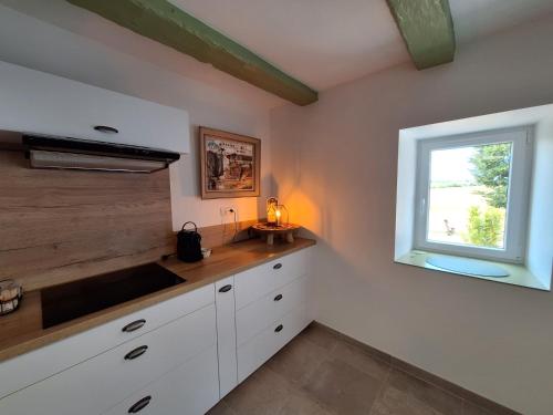 a kitchen with white cabinets and a window at Maison de la Prairie in Aubeterre-sur-Dronne