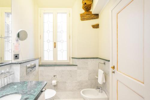 a bathroom with a sink and a toilet and a window at Art Hotel Commercianti in Bologna