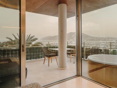 a room with a tub and a chair on a balcony at Aguas de Ibiza Grand Luxe Hotel - Small Luxury Hotel of the World in Santa Eularia des Riu