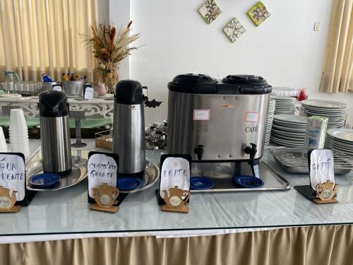 a table with two coffee machines and plates on it at VITORIA GARDEN in Águas de Lindóia