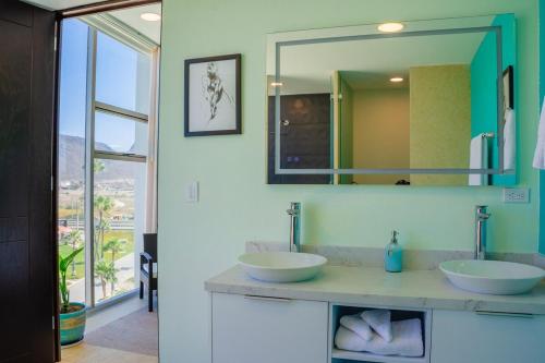 a bathroom with two sinks and a mirror at Baja Luxury With Spectacular Ocean Views Ensenada in Marisol