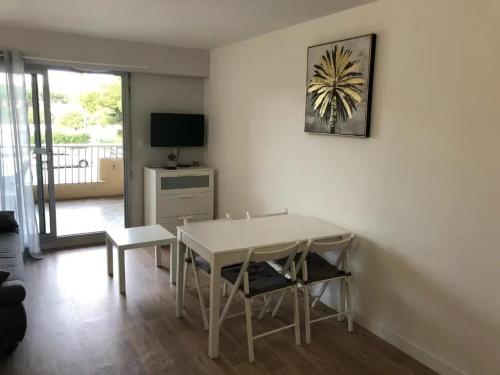un salon avec une table, des chaises et une télévision dans l'établissement Charmant studio à Hyères avec balcon - 25 m², à Hyères