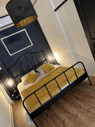 - une chambre avec un lit noir et des oreillers jaunes dans l'établissement L'Imperial, à Arles