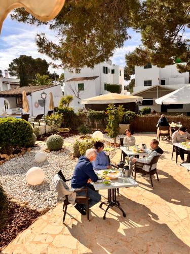 a group of people sitting at tables in a garden at Casa Ceiba Maria in Cala d´Or