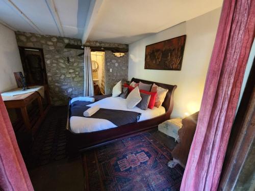 a bedroom with a bed with white sheets and red pillows at Stormsriver Backpackers - Dijembe in Stormsrivier