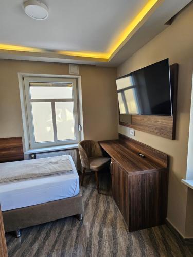 a bedroom with a bed and a flat screen tv at Hotel City Faber in Worms